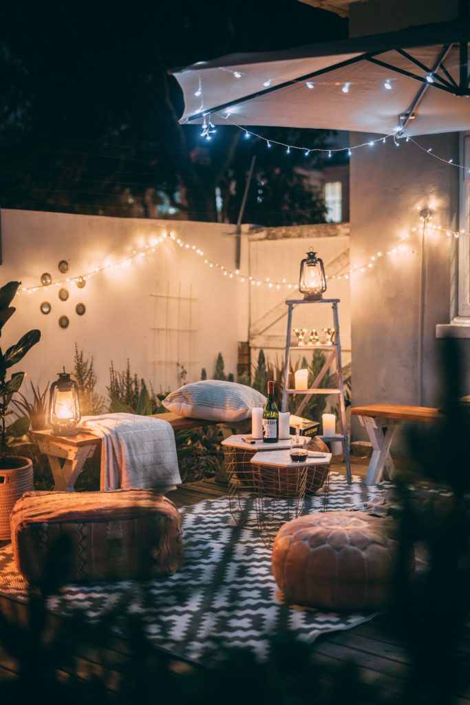 a backyard with outdoor furniture, a white privacy fence and fairy lights